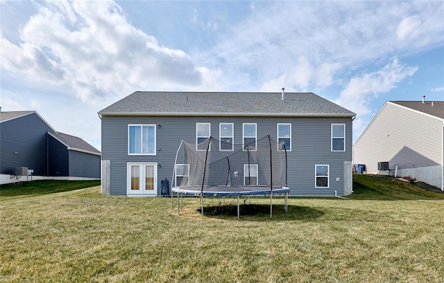 back of property with a yard and a trampoline