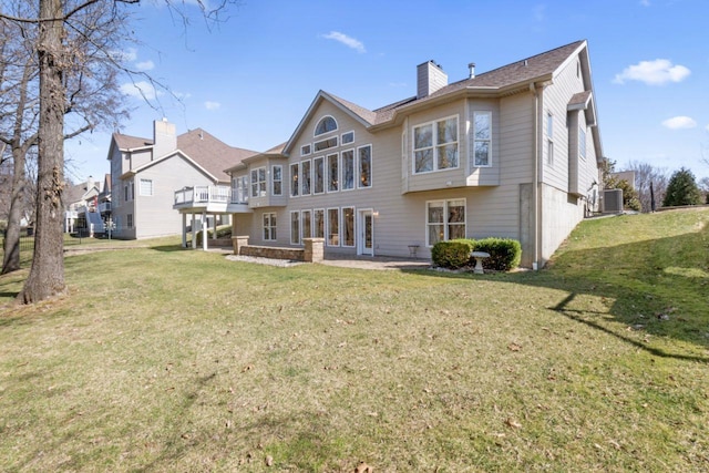 back of property featuring central air condition unit, a lawn, and a chimney