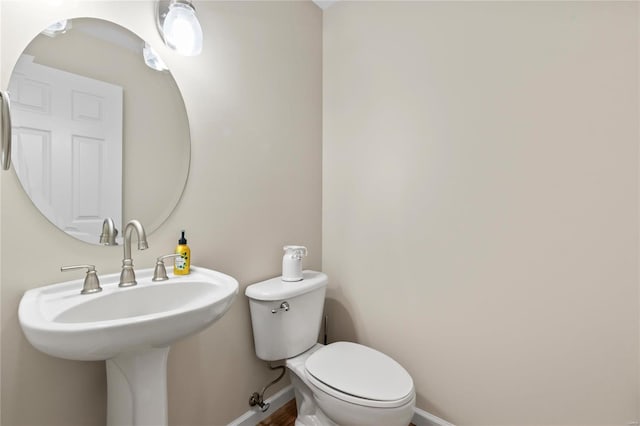 half bath with baseboards and toilet