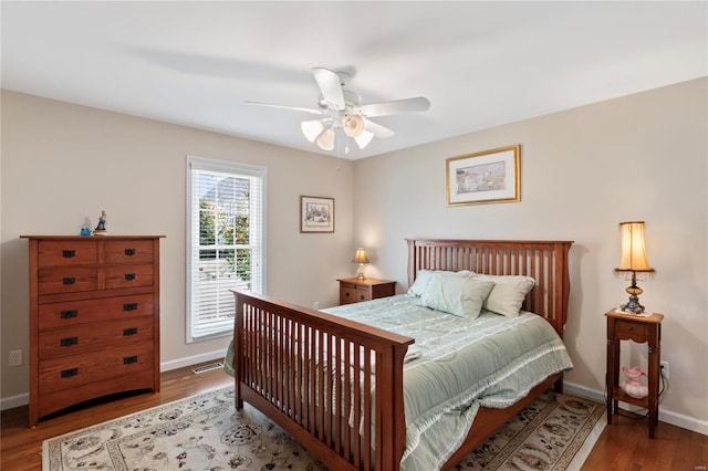 bedroom featuring visible vents, ceiling fan, baseboards, and wood finished floors