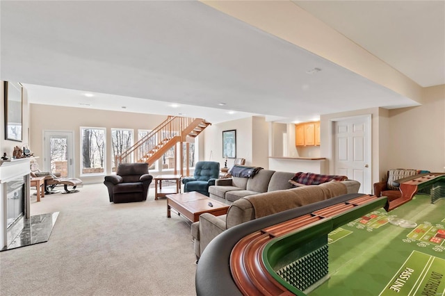 living room featuring a premium fireplace, carpet, and stairs