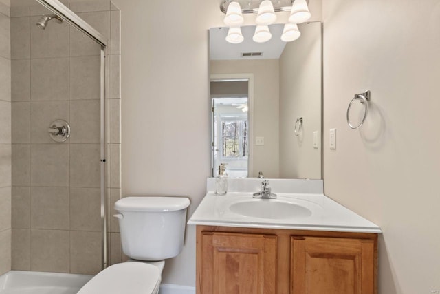 bathroom featuring vanity, toilet, visible vents, and a tile shower