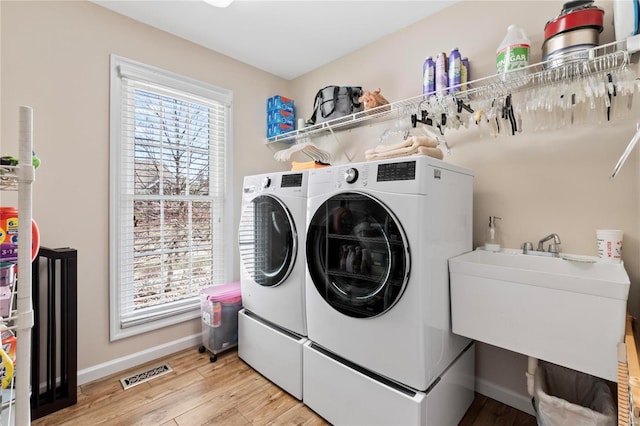 laundry room with visible vents, separate washer and dryer, light wood finished floors, baseboards, and laundry area