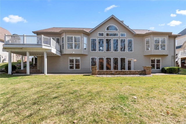 rear view of house with a wooden deck and a lawn