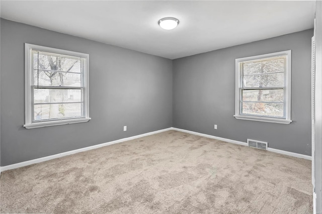 carpeted spare room with plenty of natural light, baseboards, and visible vents