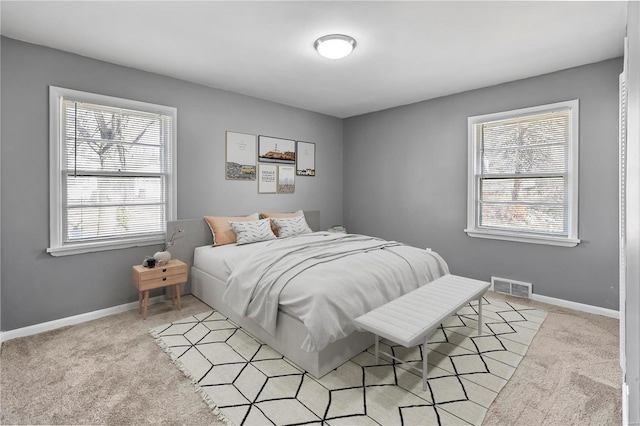 bedroom featuring light carpet, visible vents, and baseboards