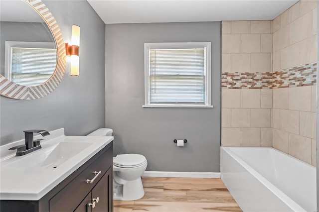 bathroom with baseboards, toilet, wood finished floors, and vanity