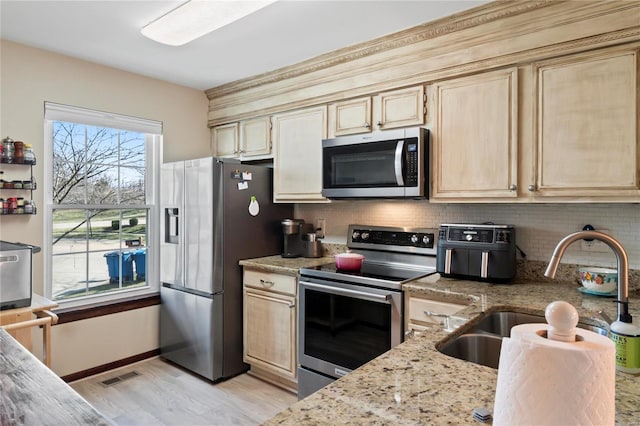 kitchen with tasteful backsplash, visible vents, light stone counters, stainless steel appliances, and a sink