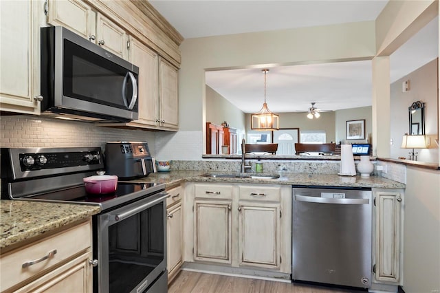 kitchen featuring a sink, light wood-style floors, appliances with stainless steel finishes, decorative backsplash, and ceiling fan