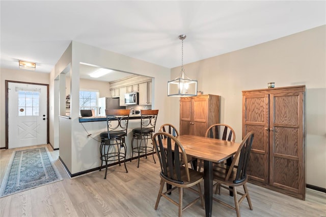 dining area with light wood-type flooring and baseboards