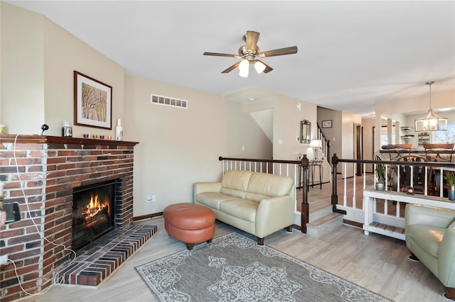 living area with visible vents, baseboards, stairway, a fireplace, and wood finished floors