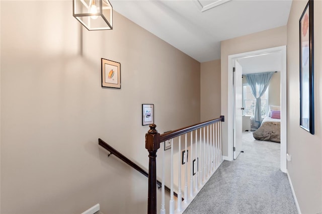 hallway featuring an upstairs landing, baseboards, and carpet floors