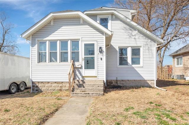 bungalow-style house with central AC unit, entry steps, and fence