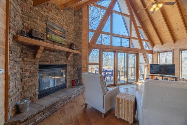 unfurnished living room with hardwood / wood-style floors, a stone fireplace, wooden ceiling, wood walls, and vaulted ceiling with beams