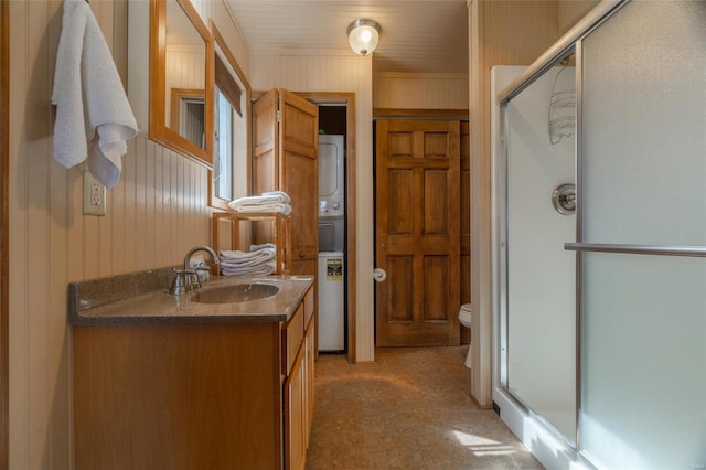 full bathroom with vanity, toilet, a shower stall, and stacked washing maching and dryer