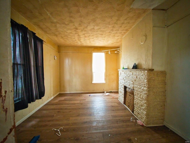 unfurnished living room featuring a stone fireplace, wood finished floors, and baseboards