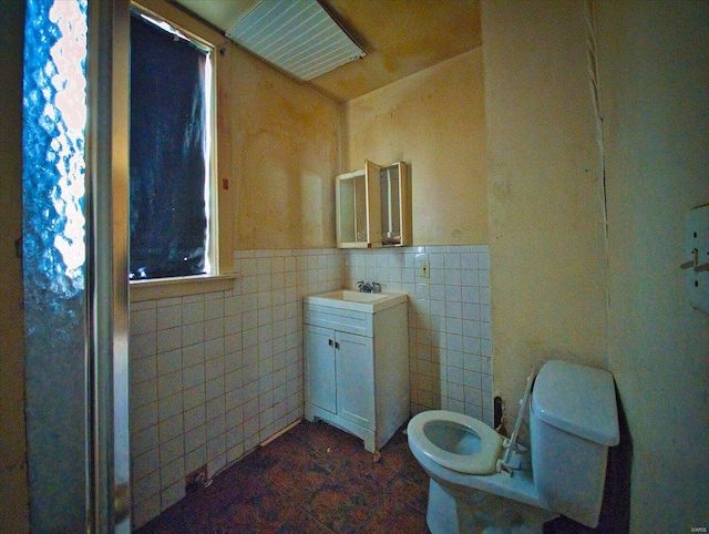 bathroom with wainscoting, tile walls, toilet, and vanity