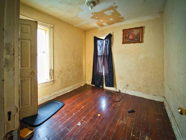 spare room featuring dark wood-style floors, plenty of natural light, and baseboards