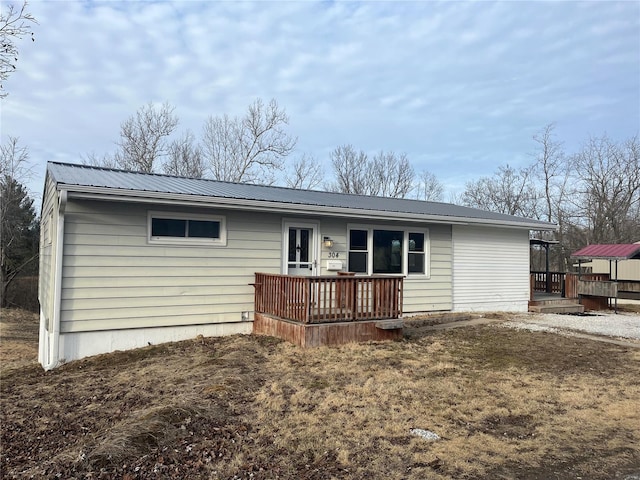 back of property featuring a deck and metal roof