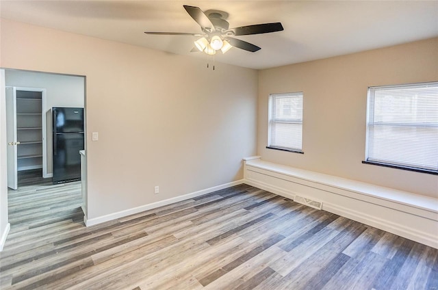 unfurnished room featuring visible vents, baseboards, wood finished floors, and a ceiling fan