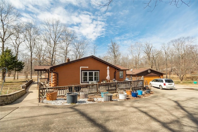 view of front of house with a chimney, a wooden deck, and log siding