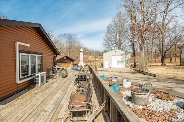 deck featuring an outbuilding, concrete driveway, ac unit, and a detached garage