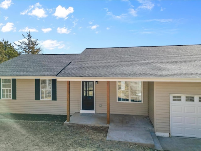 view of front of property featuring a garage and roof with shingles