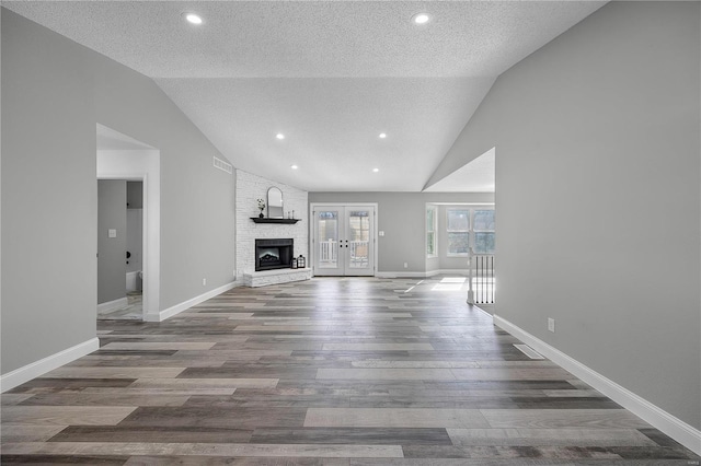 unfurnished living room featuring a textured ceiling, baseboards, wood finished floors, and french doors