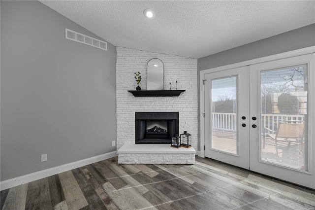 unfurnished living room with lofted ceiling, visible vents, a textured ceiling, and french doors