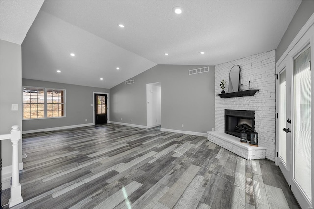 unfurnished living room featuring dark wood finished floors, a large fireplace, visible vents, and vaulted ceiling