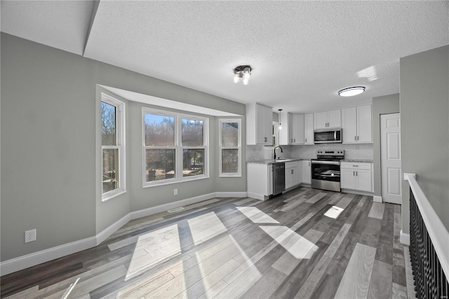 kitchen featuring light countertops, appliances with stainless steel finishes, white cabinets, a sink, and wood finished floors