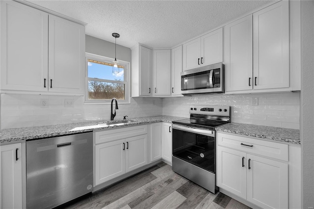 kitchen featuring white cabinets, light wood finished floors, stainless steel appliances, and a sink