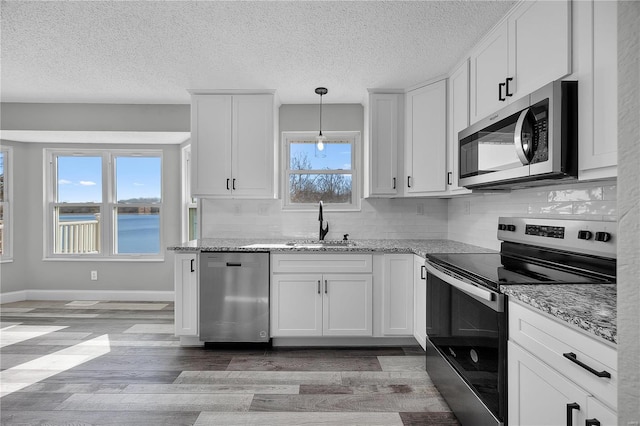 kitchen with tasteful backsplash, light stone counters, stainless steel appliances, light wood-style floors, and a sink