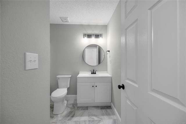 bathroom featuring a textured wall, toilet, a textured ceiling, vanity, and baseboards