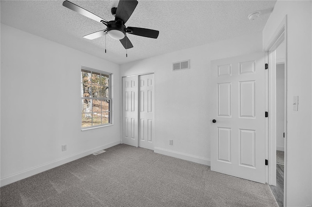 unfurnished bedroom featuring baseboards, visible vents, carpet, a textured ceiling, and a closet