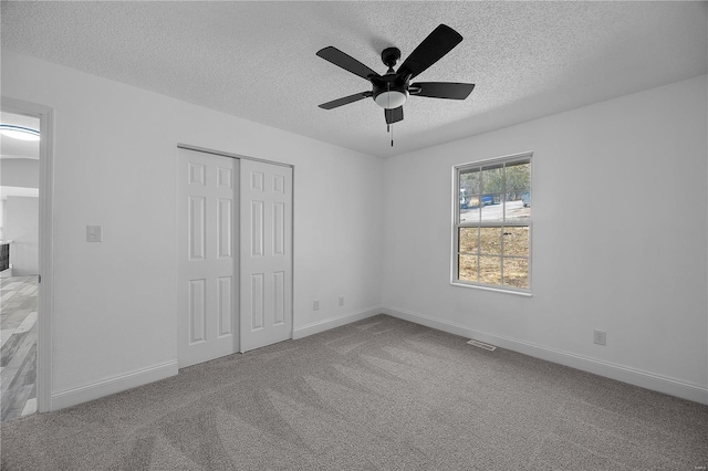 unfurnished bedroom with baseboards, visible vents, a textured ceiling, carpet flooring, and a closet