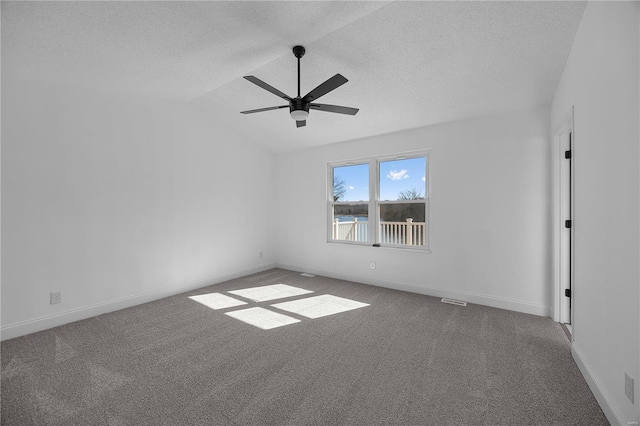 empty room with a textured ceiling, baseboards, carpet flooring, and lofted ceiling