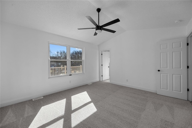 unfurnished bedroom featuring lofted ceiling, a textured ceiling, carpet flooring, and visible vents