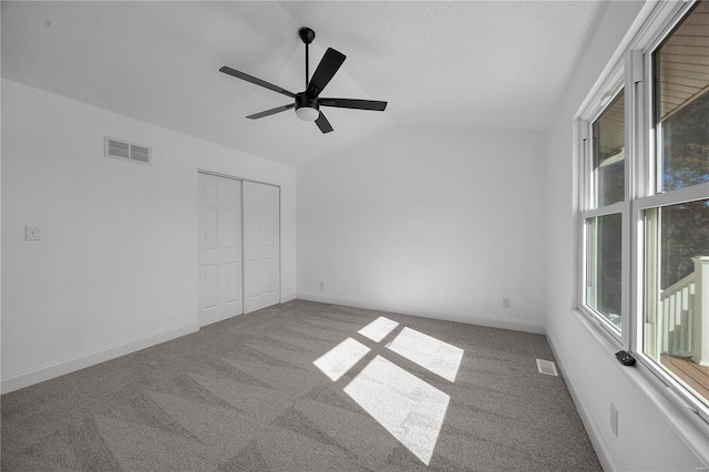 unfurnished bedroom featuring lofted ceiling, visible vents, and carpet