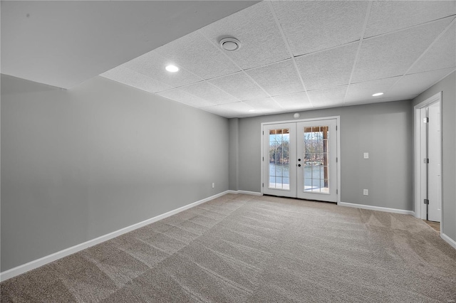 unfurnished room with carpet floors, baseboards, a drop ceiling, and french doors