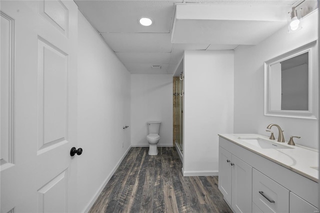 bathroom with a stall shower, baseboards, toilet, wood finished floors, and vanity