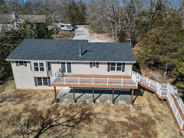 rear view of property featuring a shingled roof and a wooden deck