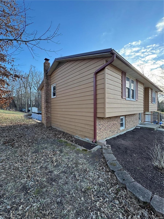 view of home's exterior with a chimney and brick siding