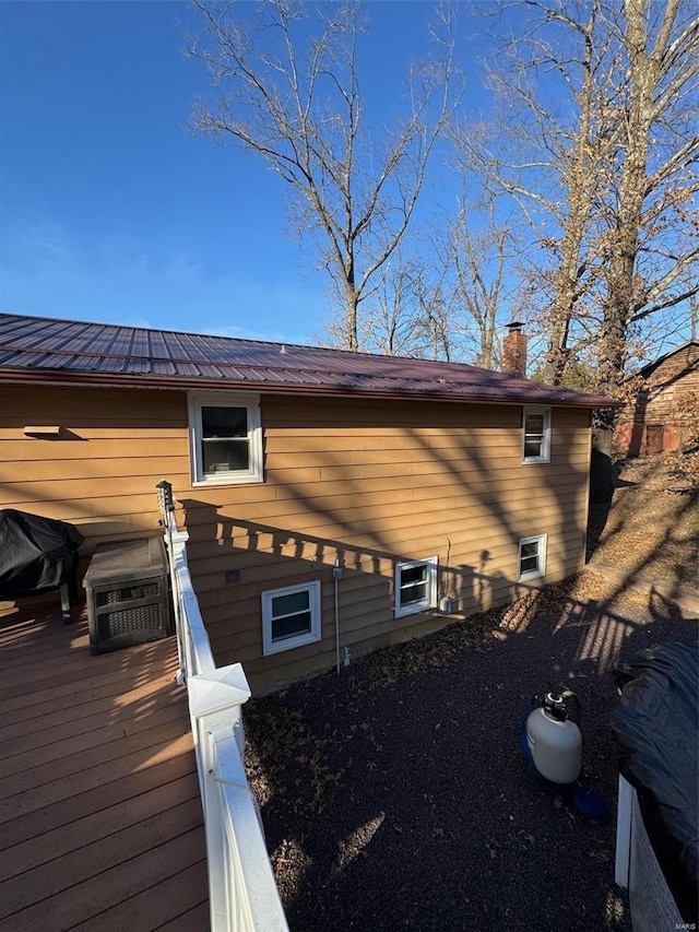 view of property exterior with a deck, metal roof, and a chimney