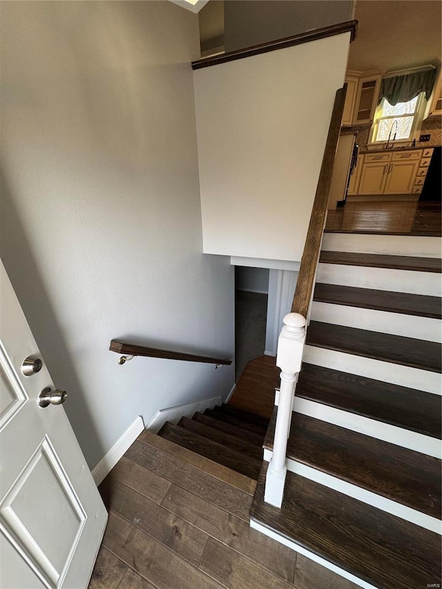 staircase with baseboards and wood finished floors