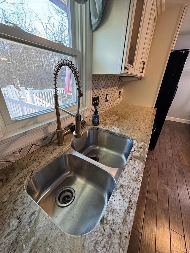 details featuring dark wood-style floors, light stone counters, decorative backsplash, and a sink