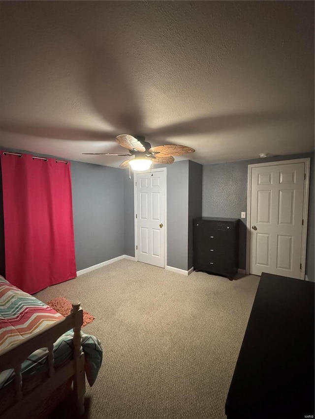 carpeted bedroom featuring a ceiling fan, a textured ceiling, and baseboards