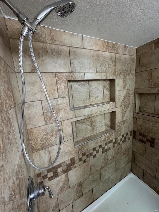 room details featuring a textured ceiling and tiled shower