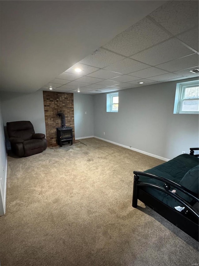 interior space featuring a paneled ceiling, recessed lighting, carpet flooring, baseboards, and a wood stove