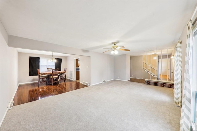 carpeted living room featuring baseboards, visible vents, and a ceiling fan